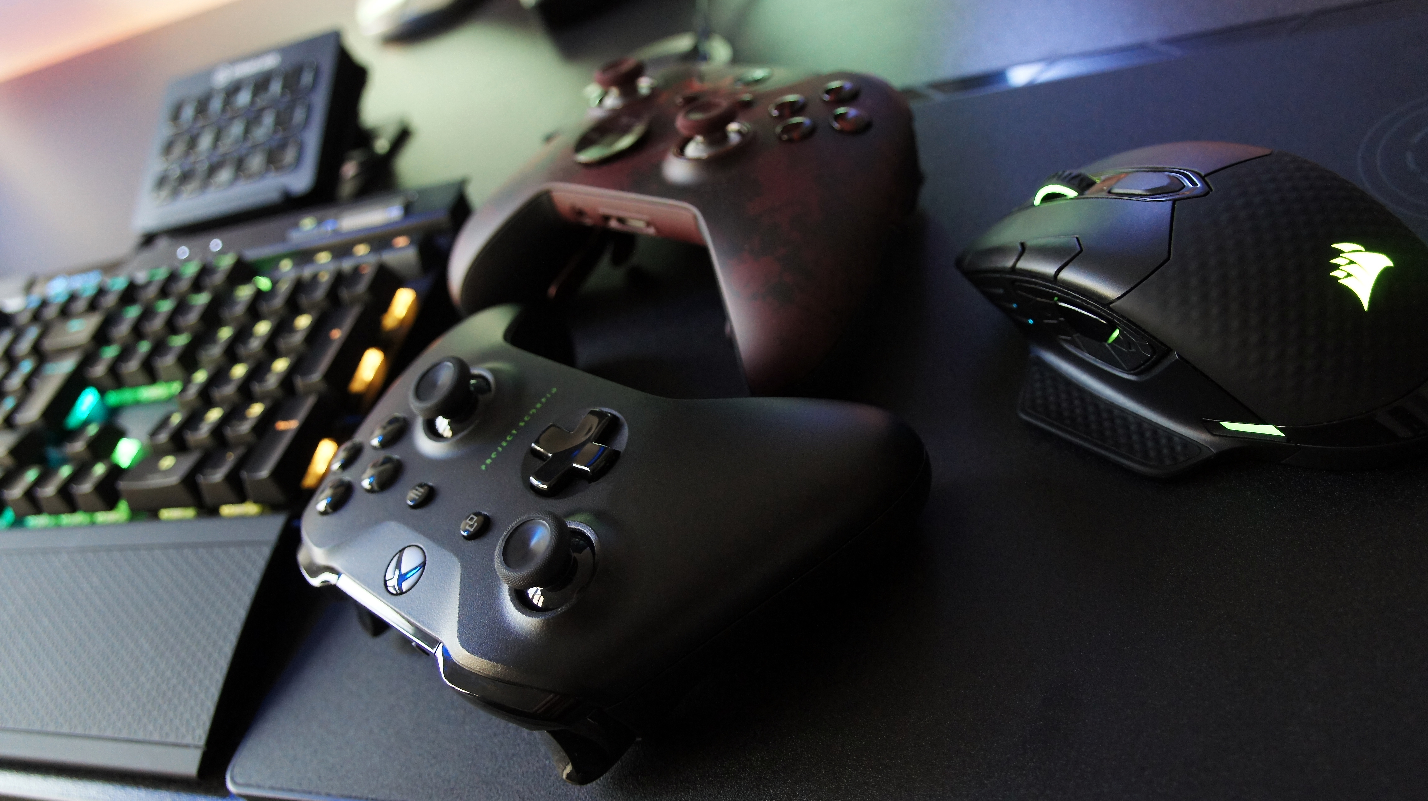 Gaming keyboard and controllers on a desk for an online play setup